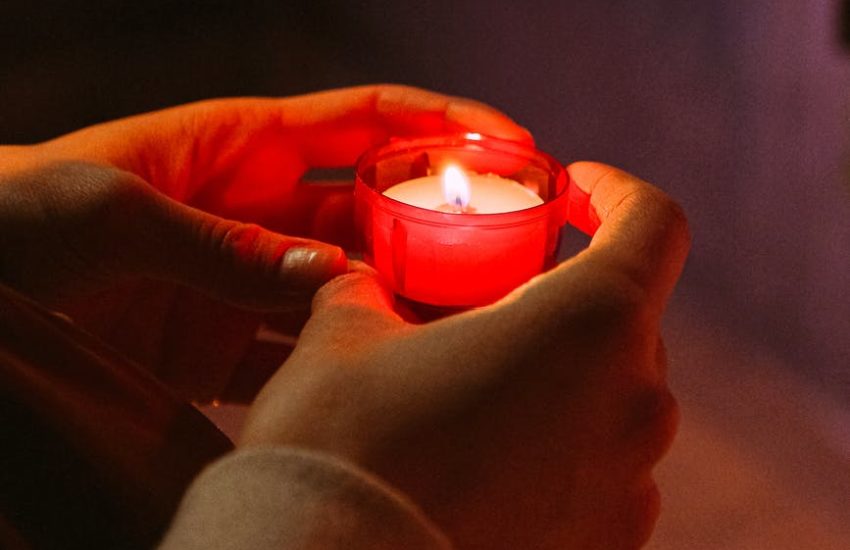 person holding red candle in a dark room